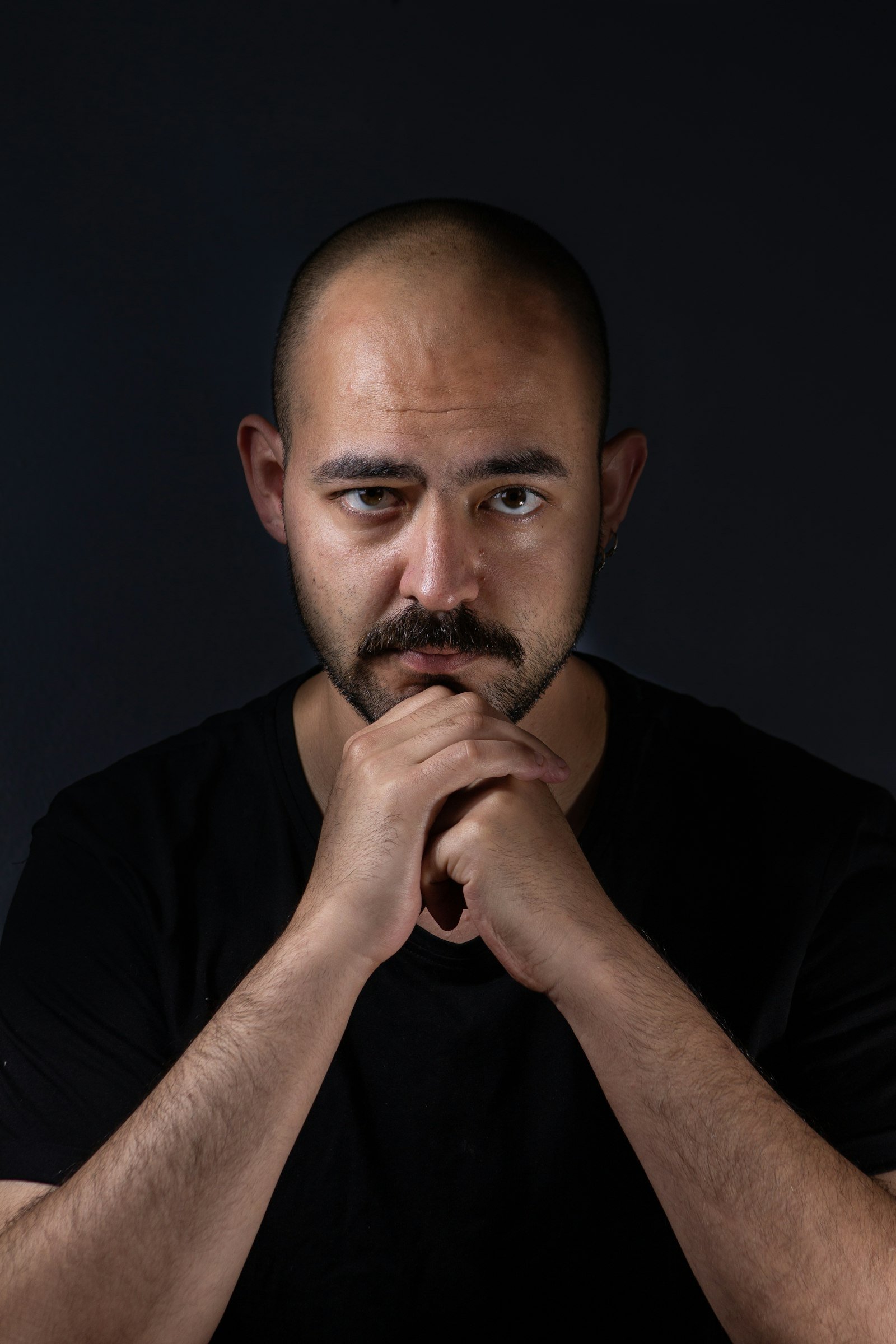 Əllərini birləşdirib düşünən kişinin portreti